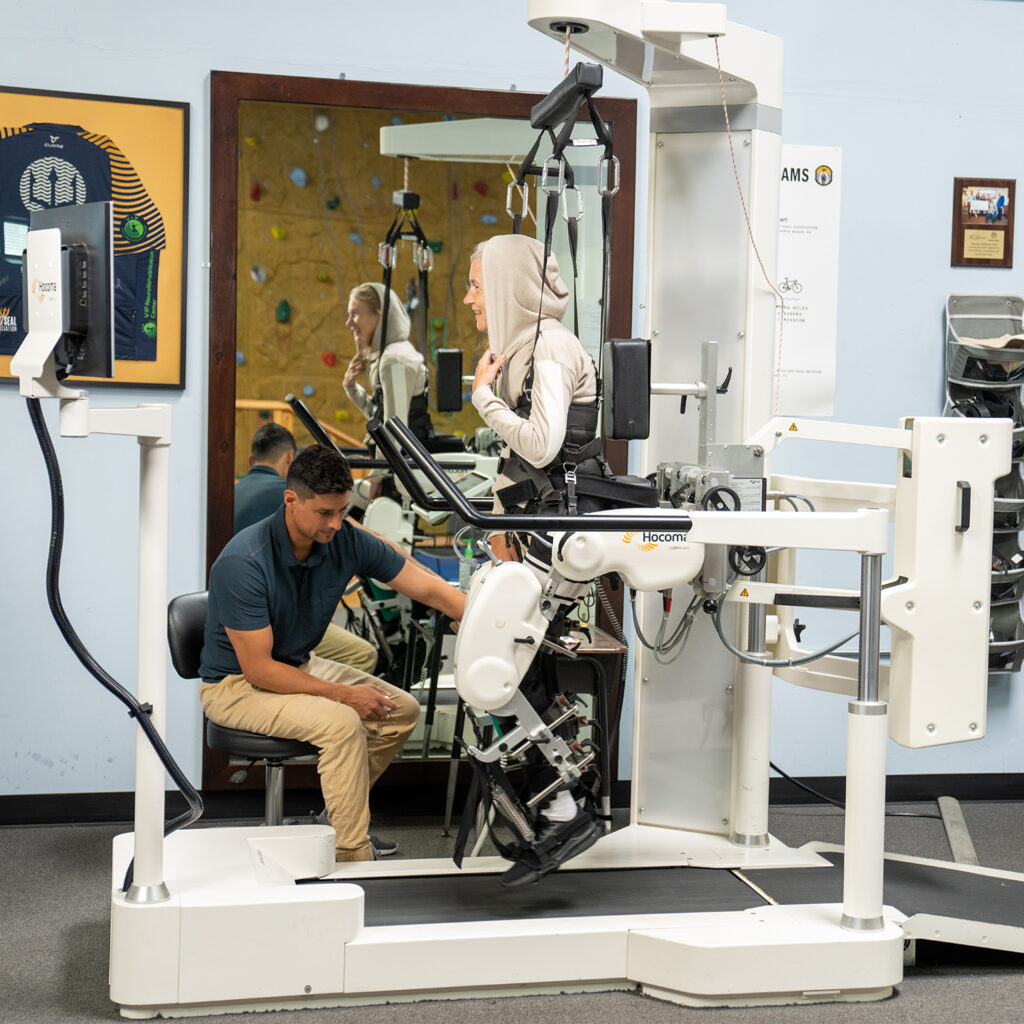 A woman exercises in a Lokomat while a physical observes